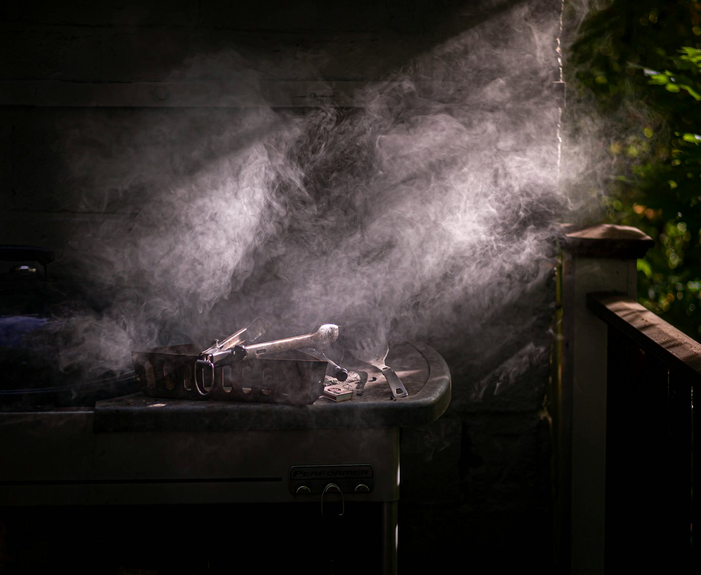 Smoke rises from a charcoal grill sitting on a patio.