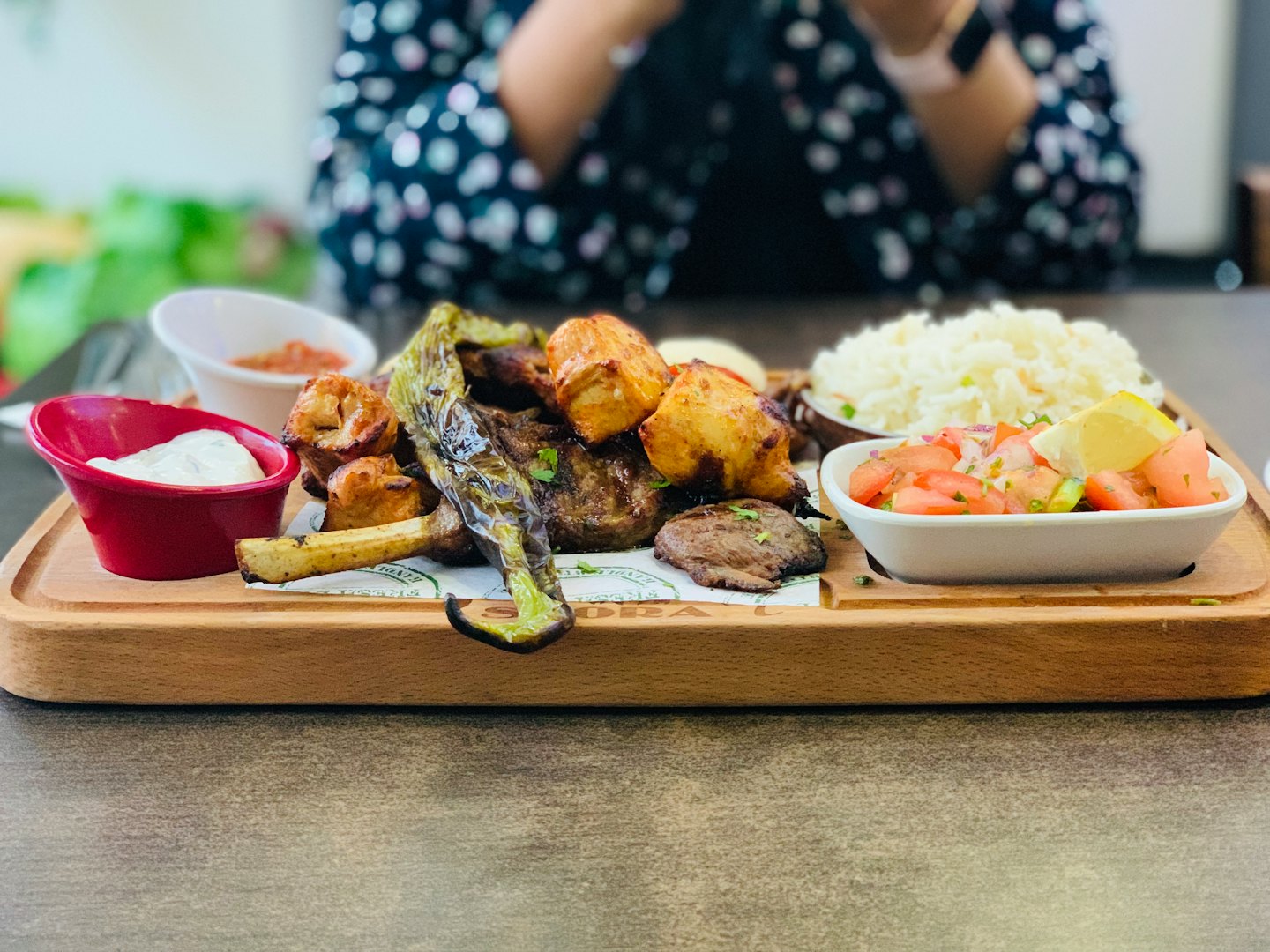 Grilled meat platter with rice, salad, and dipping sauces.