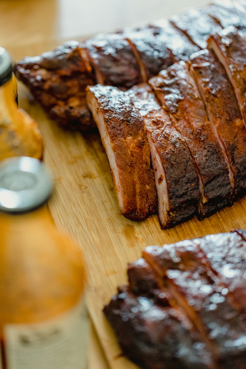 Succulent sliced barbecue ribs rest on a wooden cutting board.